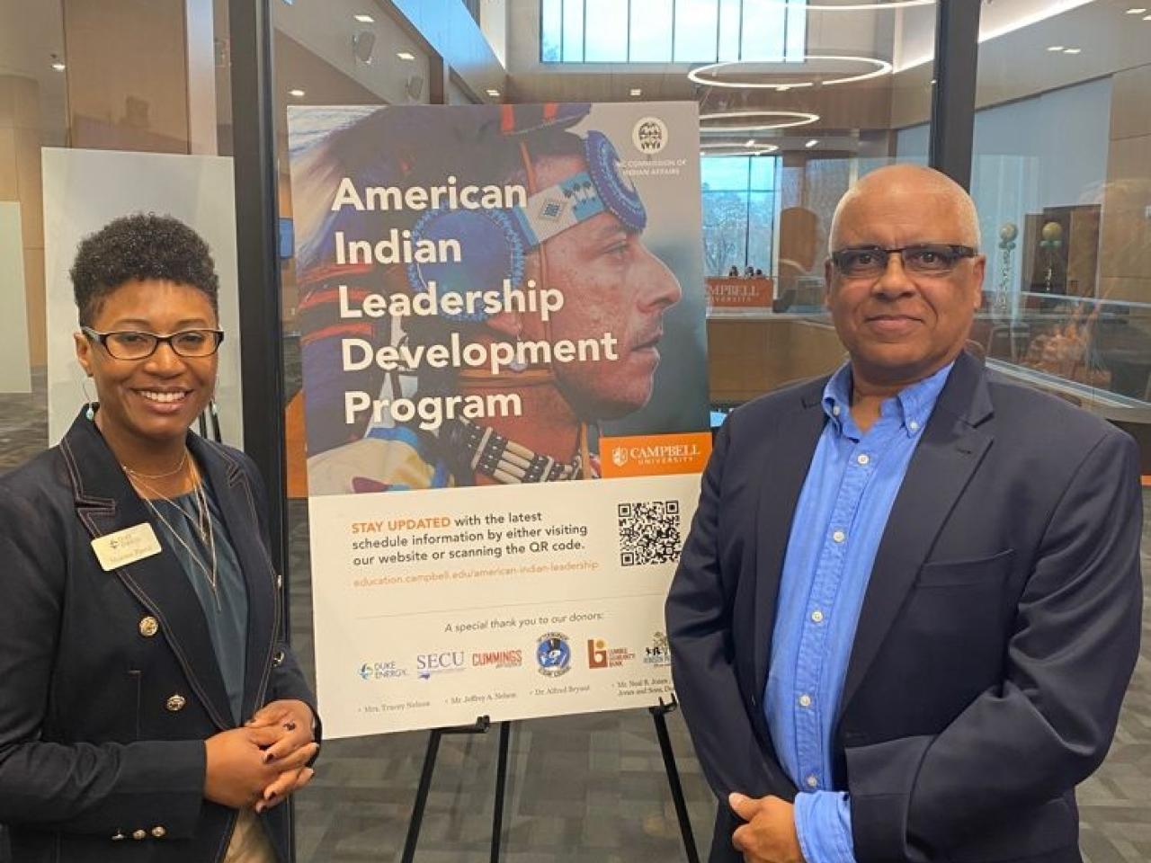 Two people stand beside a poster "American Indian Leadership Development Program."