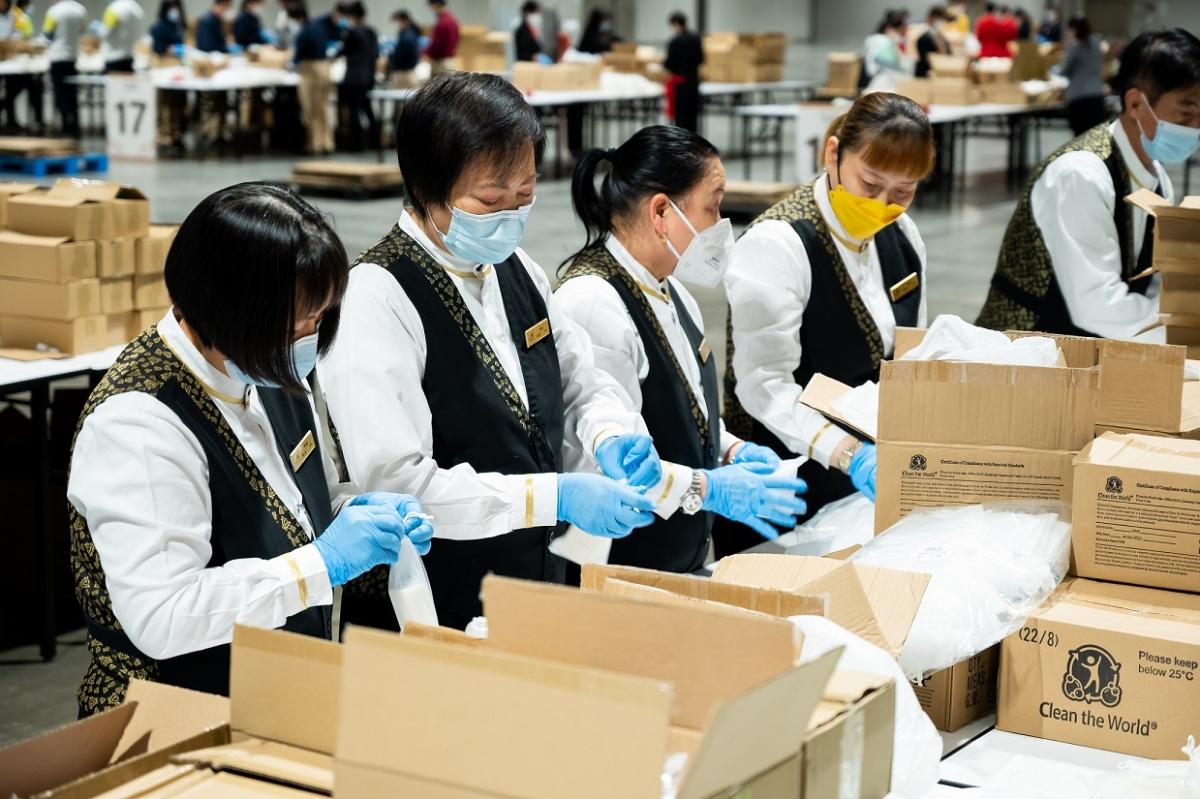People in masks and gloves working with boxes on tables