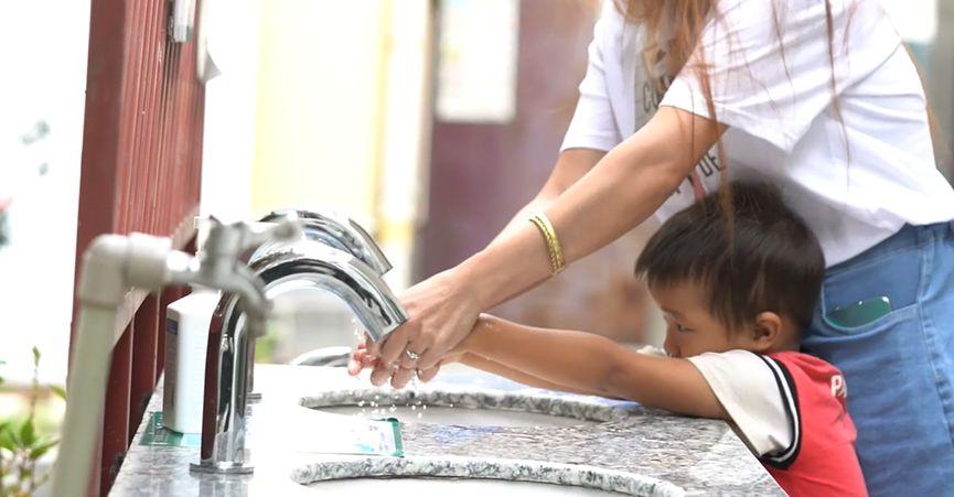 An adult helping a child wash their hands