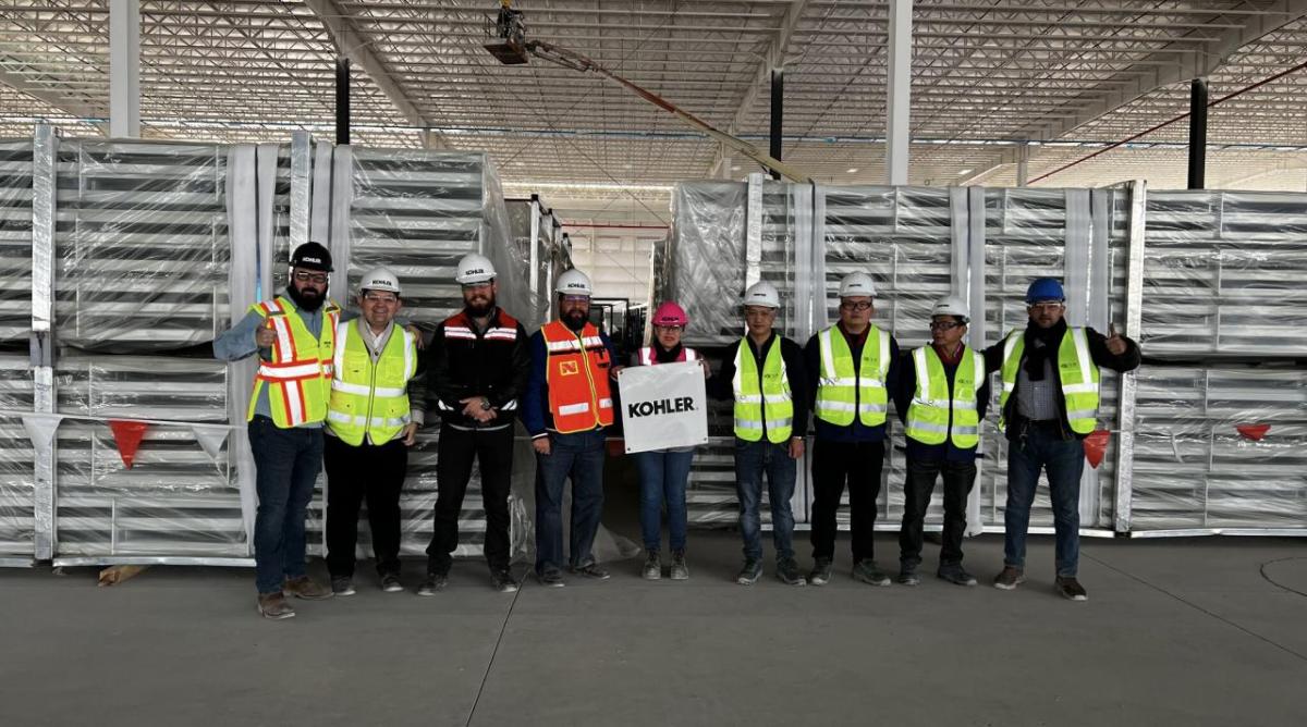 Group standing together in manufacturing plant wearing reflective vests