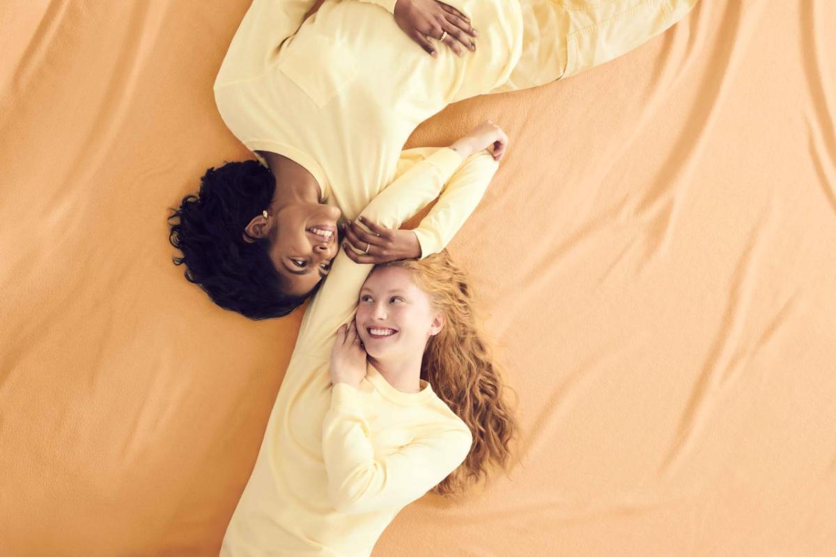 Two models wearing yellow Comfort Colors clothing, lying against a yellow backdrop