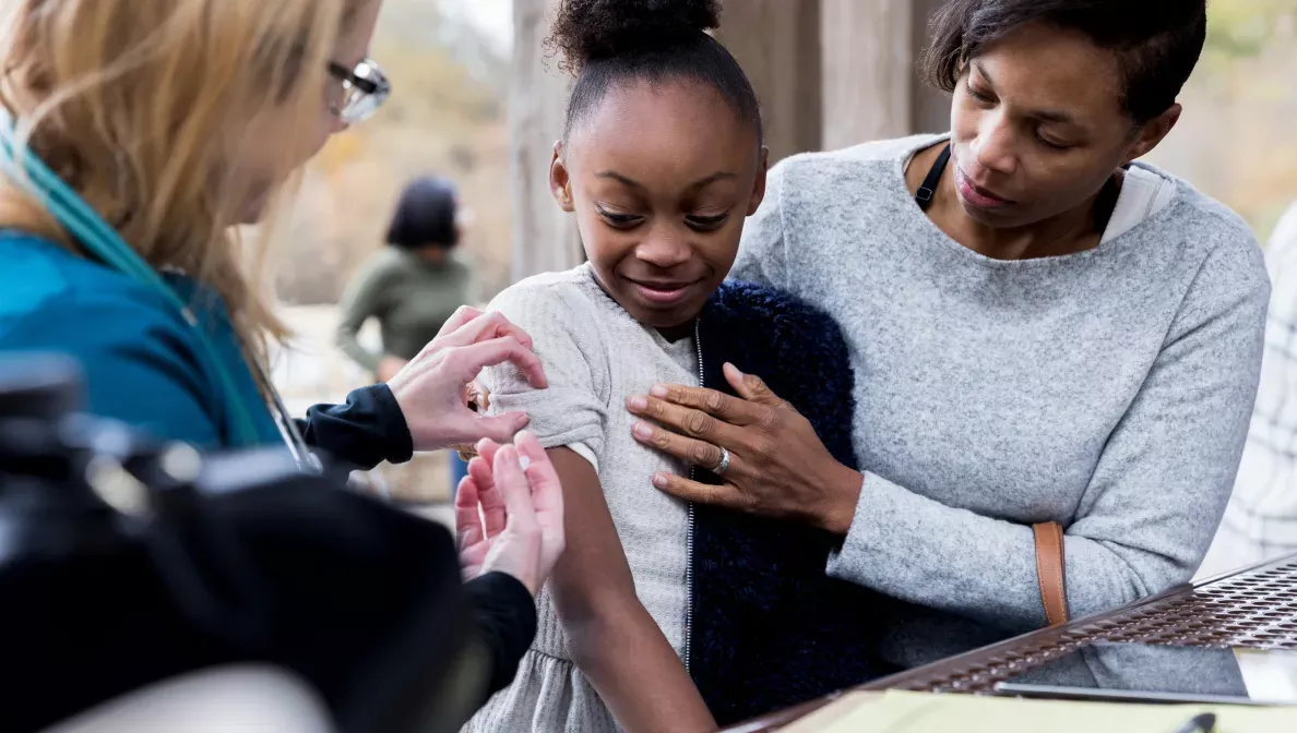 A girl receiving a vaccination by a doctor 