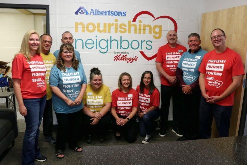 People standing in front of Albertsons Companies Foundation's Nourishing Neighbors and Kellogg's sign