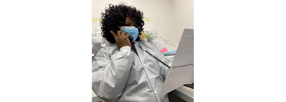 Marissa McGhee wearing a face mask, using a telephone while looking at a piece of paper