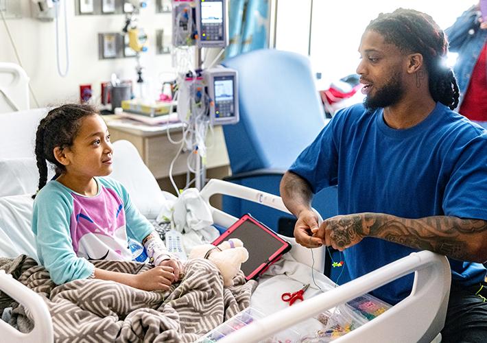 Damar Hamlin talking with a child in a hospital bed.