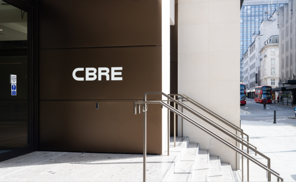 Exterior sign on a building "CBRE" nest to a short staircase.