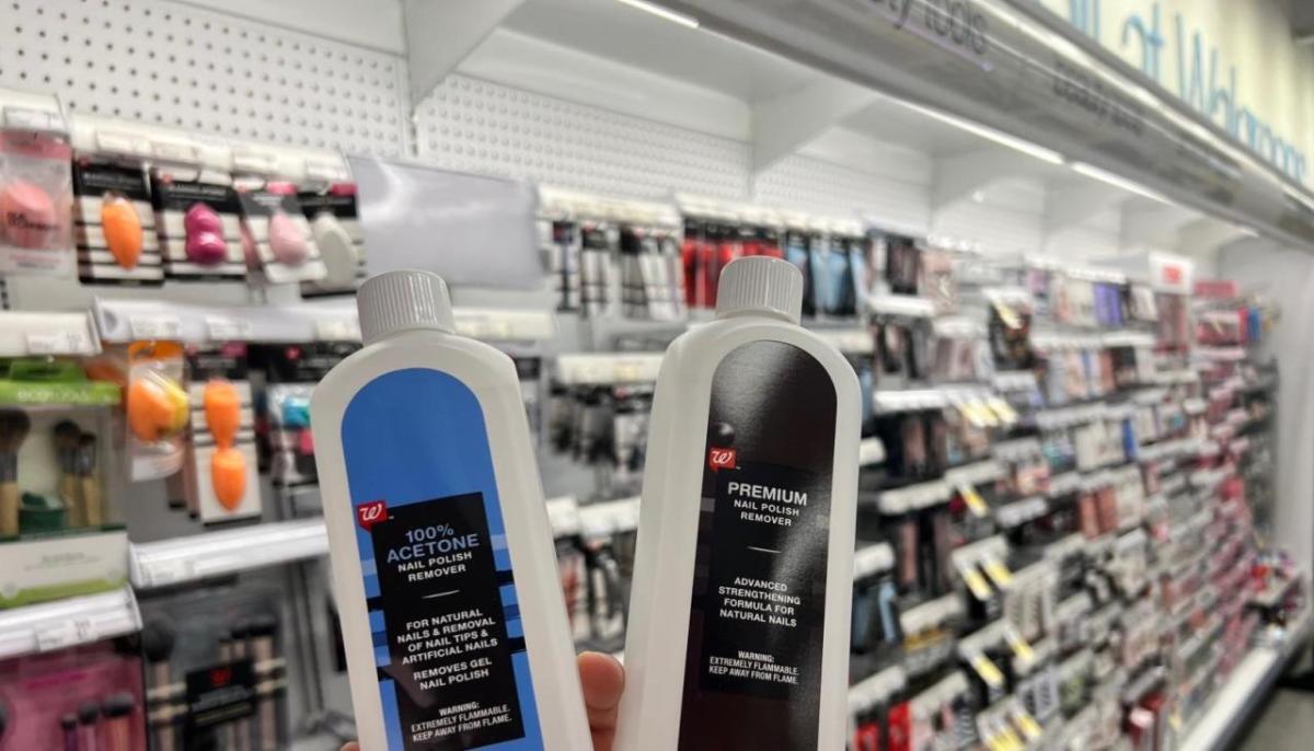 Two bottles of nail polish remover in slightly different packaging, held up in front of an aisle of beauty products.