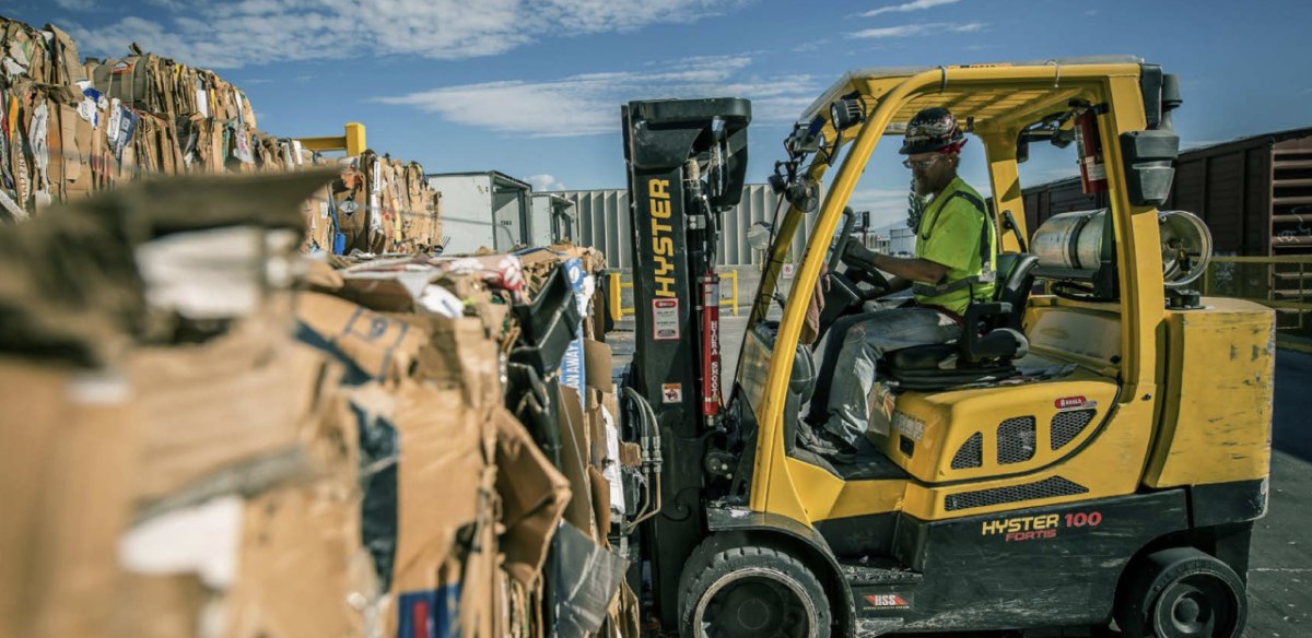 forklift working in an outdoor field of recovered cardboard