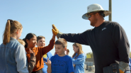 An employee in a hard hat gives a high five to a child.