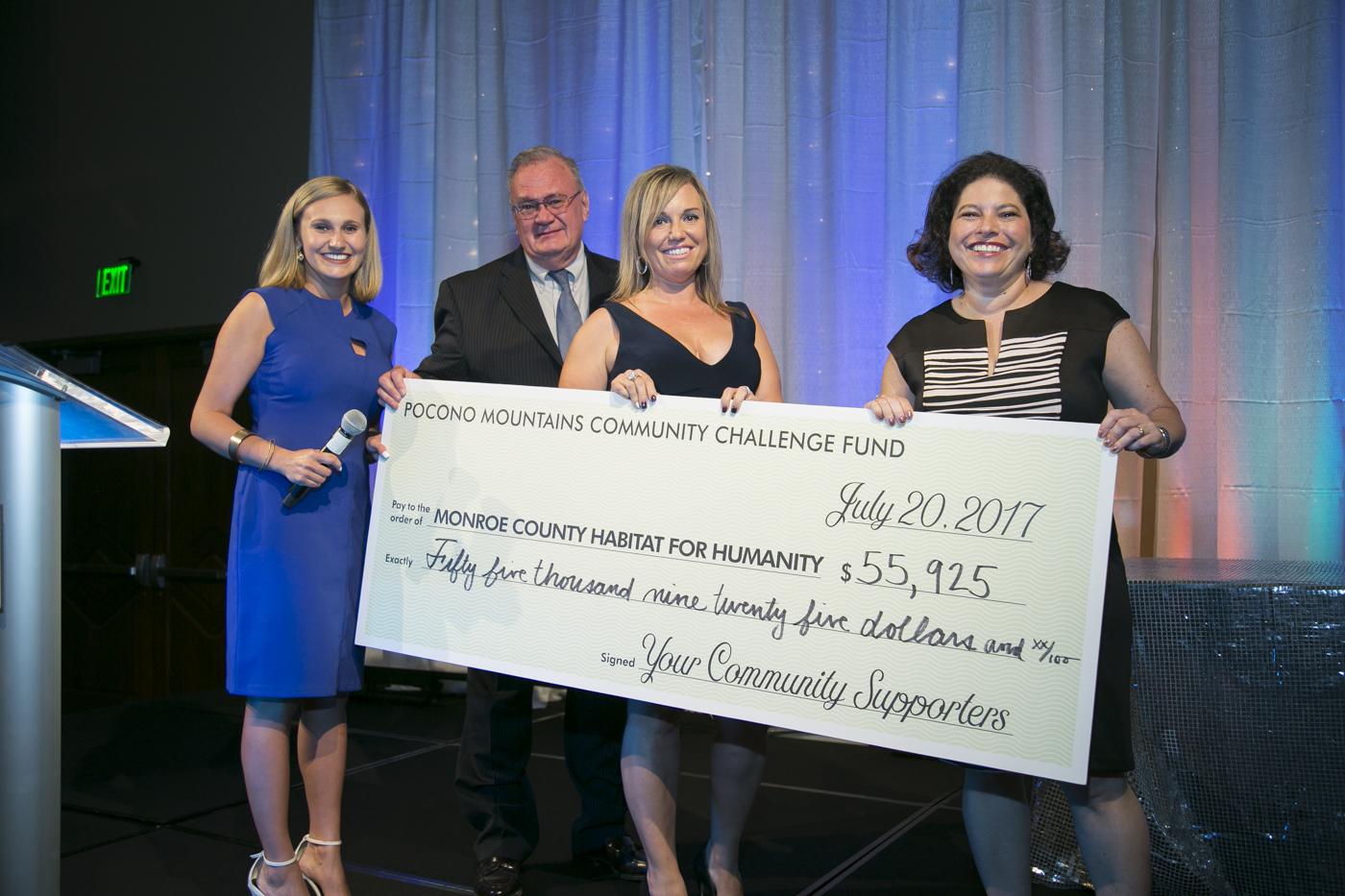 (L-R) Eyewitness News Reporter Brianna Strunk, Monroe County Habitat for Humanity Board President Gary Samboy, Monroe County Habitat for Humanity Executive Director Kelly Kemmerer, and Sanofi Pasteur Director of North American Corporate Responsibility Ellyn Schindler take the stage at the 2017 Pocono Mountains Community Fundraiser. Habitat for Humanity was one of five local non-profit recipients to receive funding from Sanofi Pasteur’s signature local Corporate Social Responsibility event.
