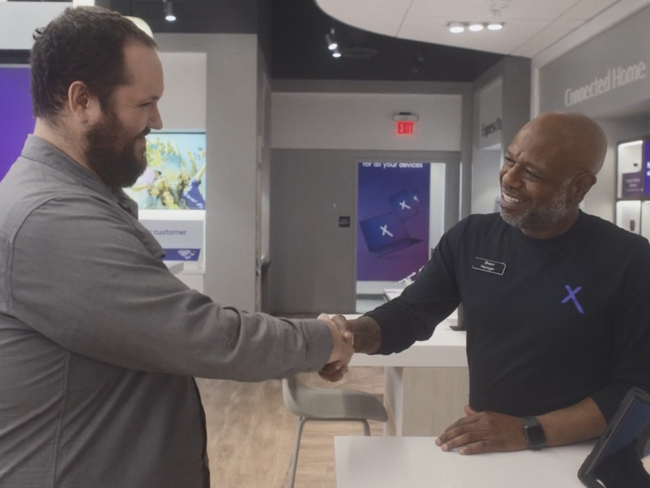 An employee and customer smiling and shaking hands.