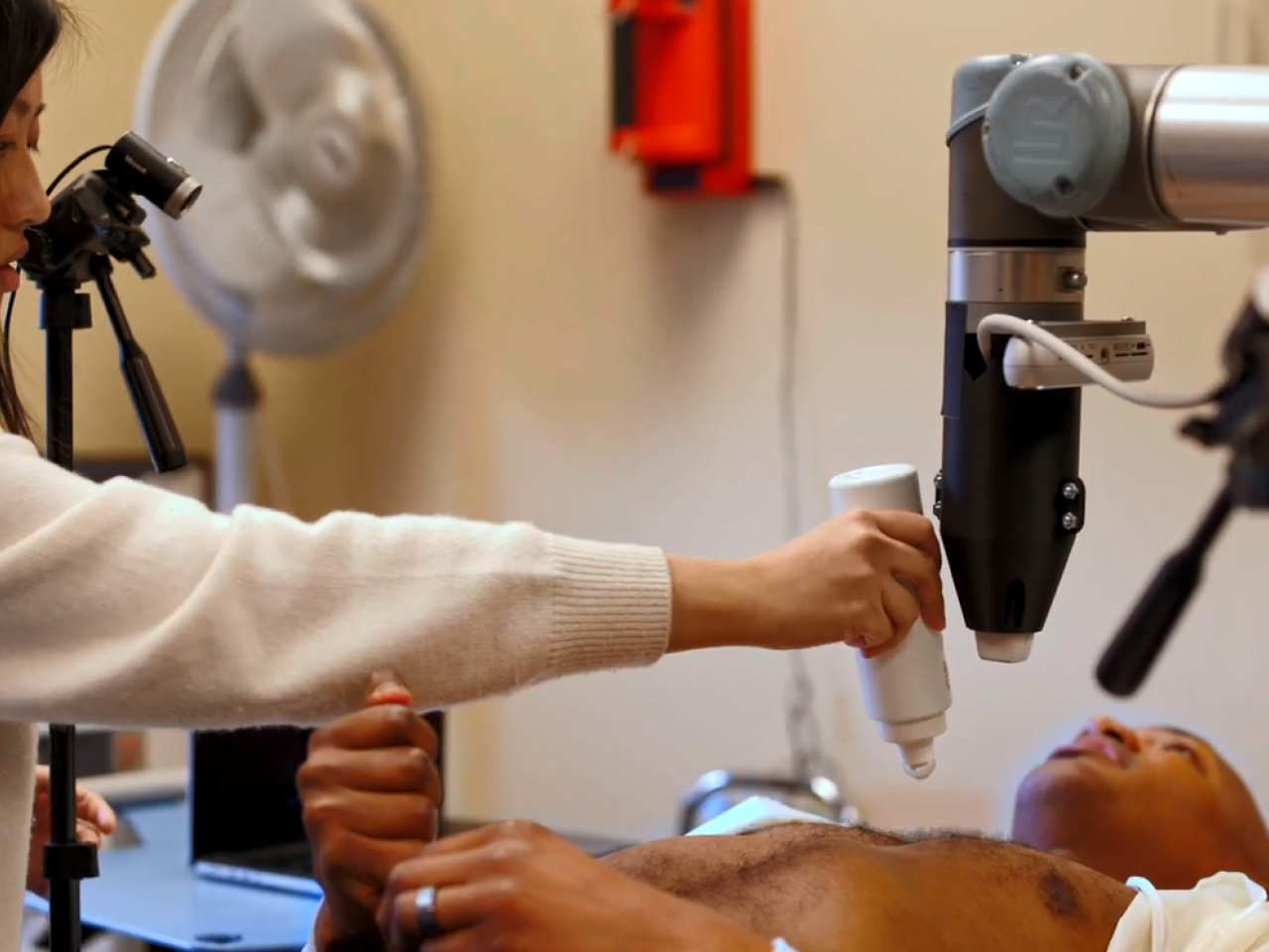 A person laying down receiving an ultrasound, a medical professional applying gel to their chest.