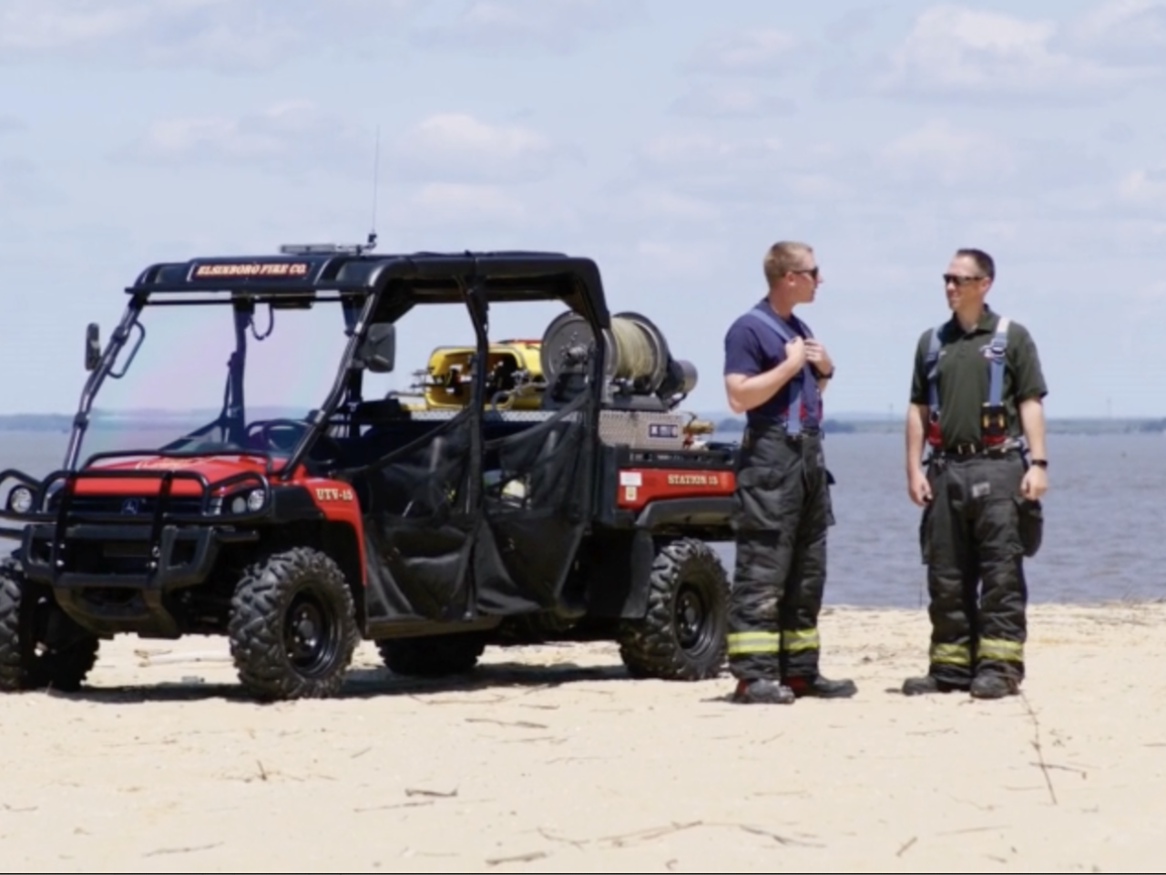 The Fire Department's utility terrain vehicle parked on a beach with two men standing nearby