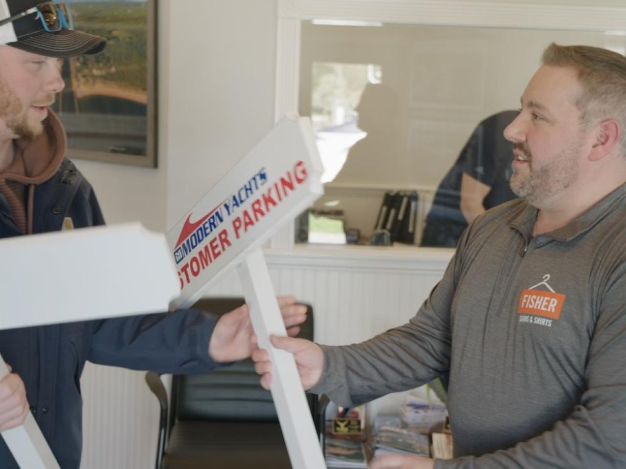 Ron Fisher, right, delivers custom signs made by Fisher Signs & Shirts.