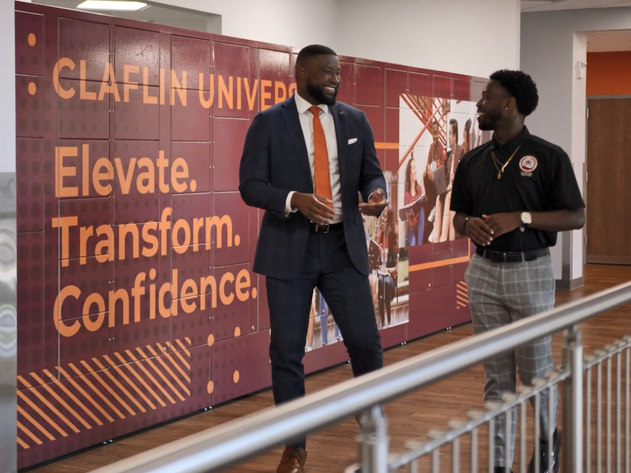 The Dean and a student smiling and talking as they walk through a hall way at the school.