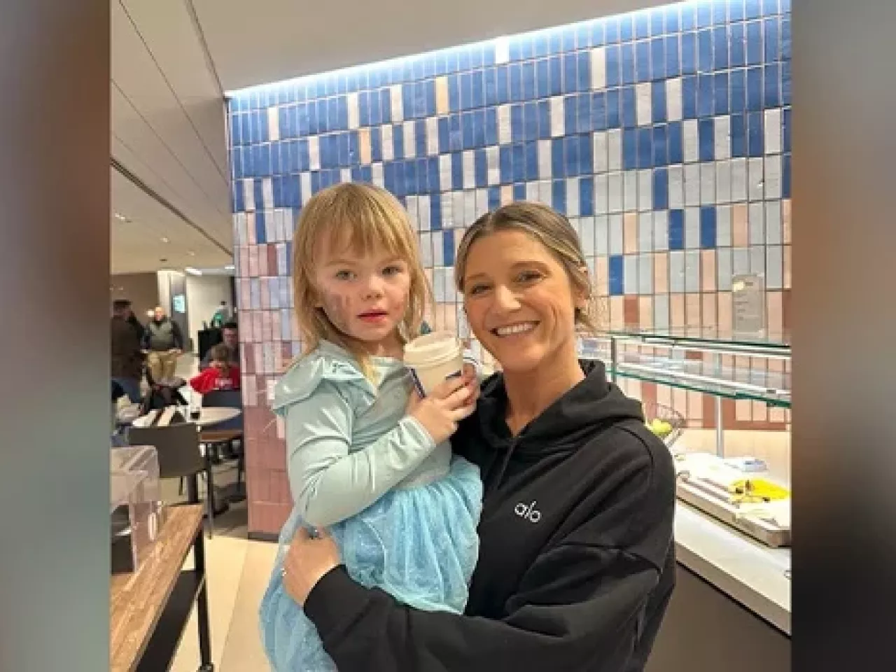 Britney Ruby Miller holding a child in a cafeteria setting.