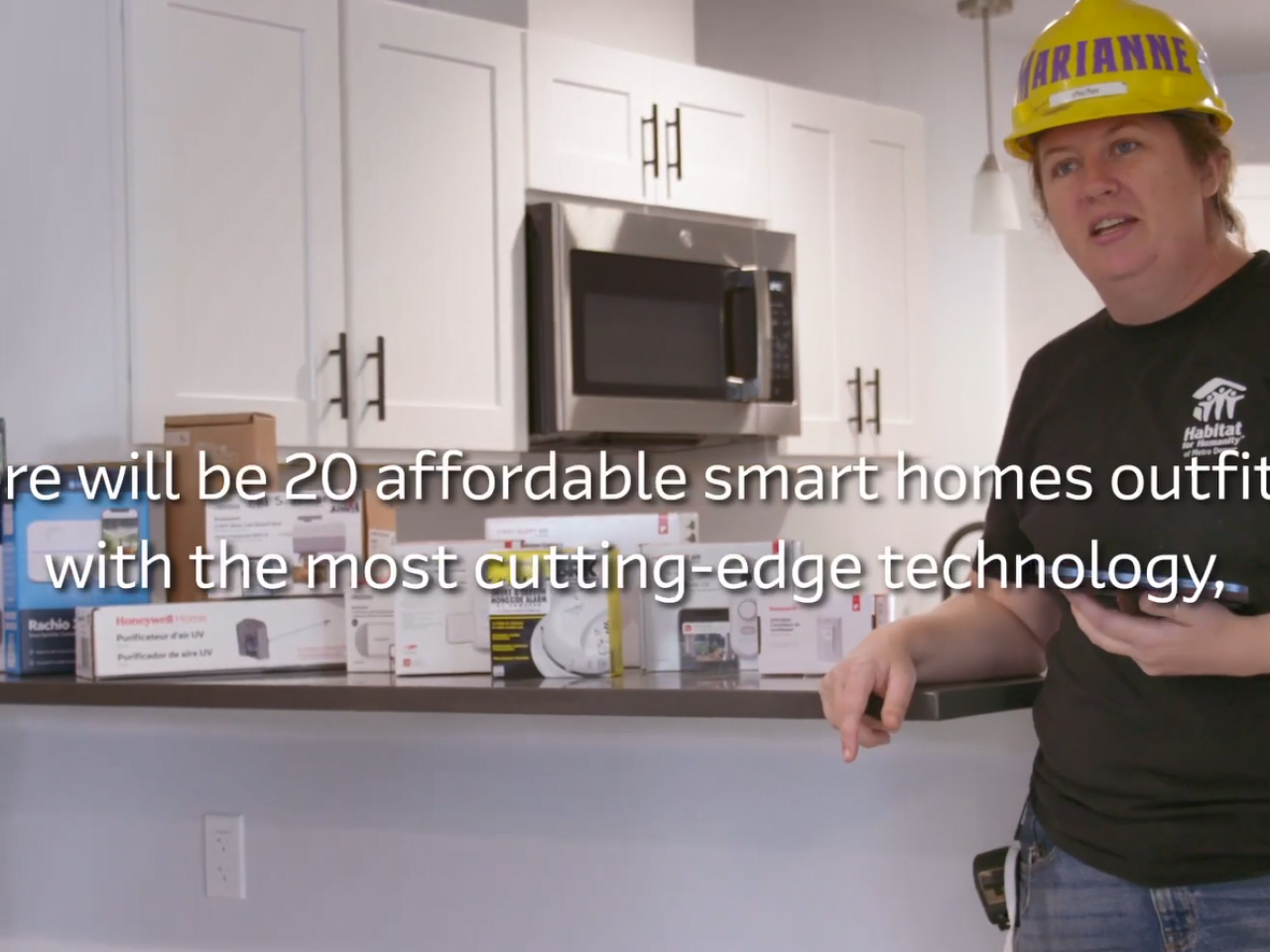 A worker standing next to a kithen island with many different tech products on it.