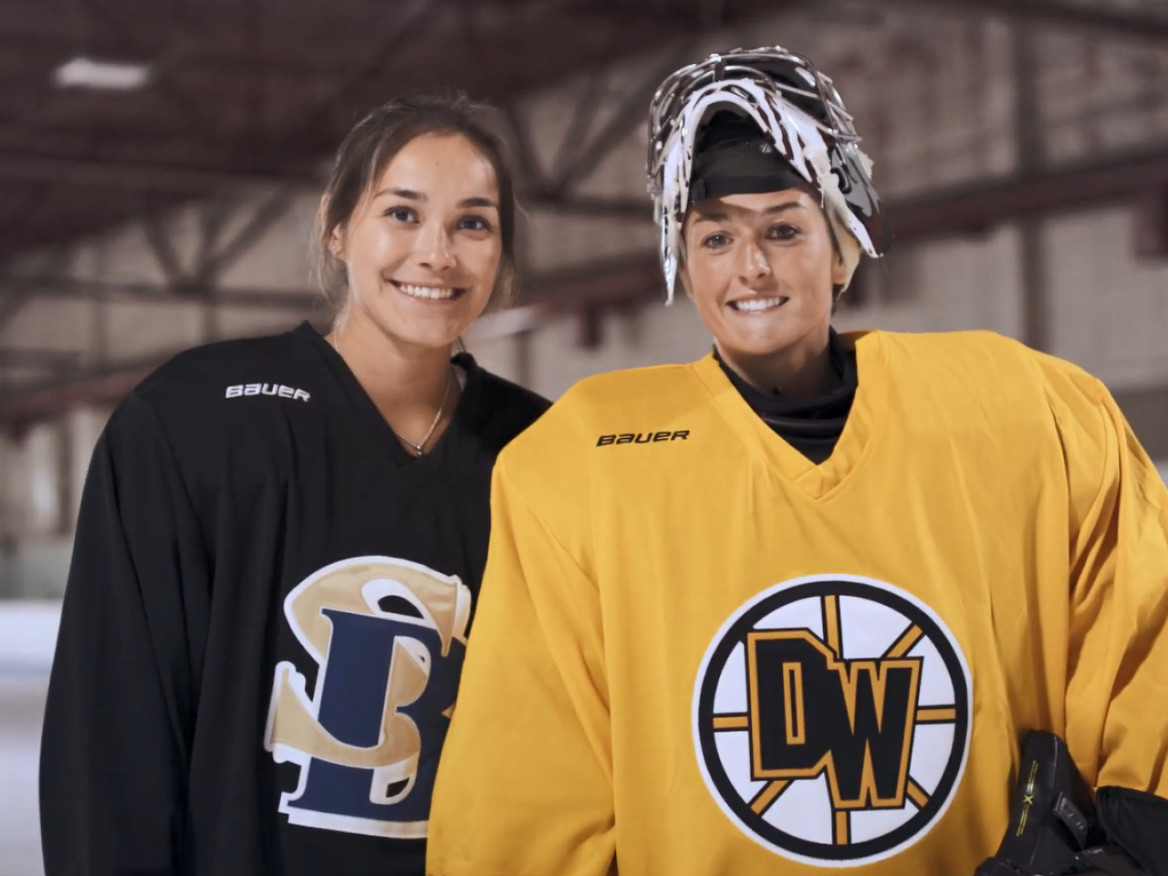 Two Alumni in hockey uniforms posed together on an ice rink.