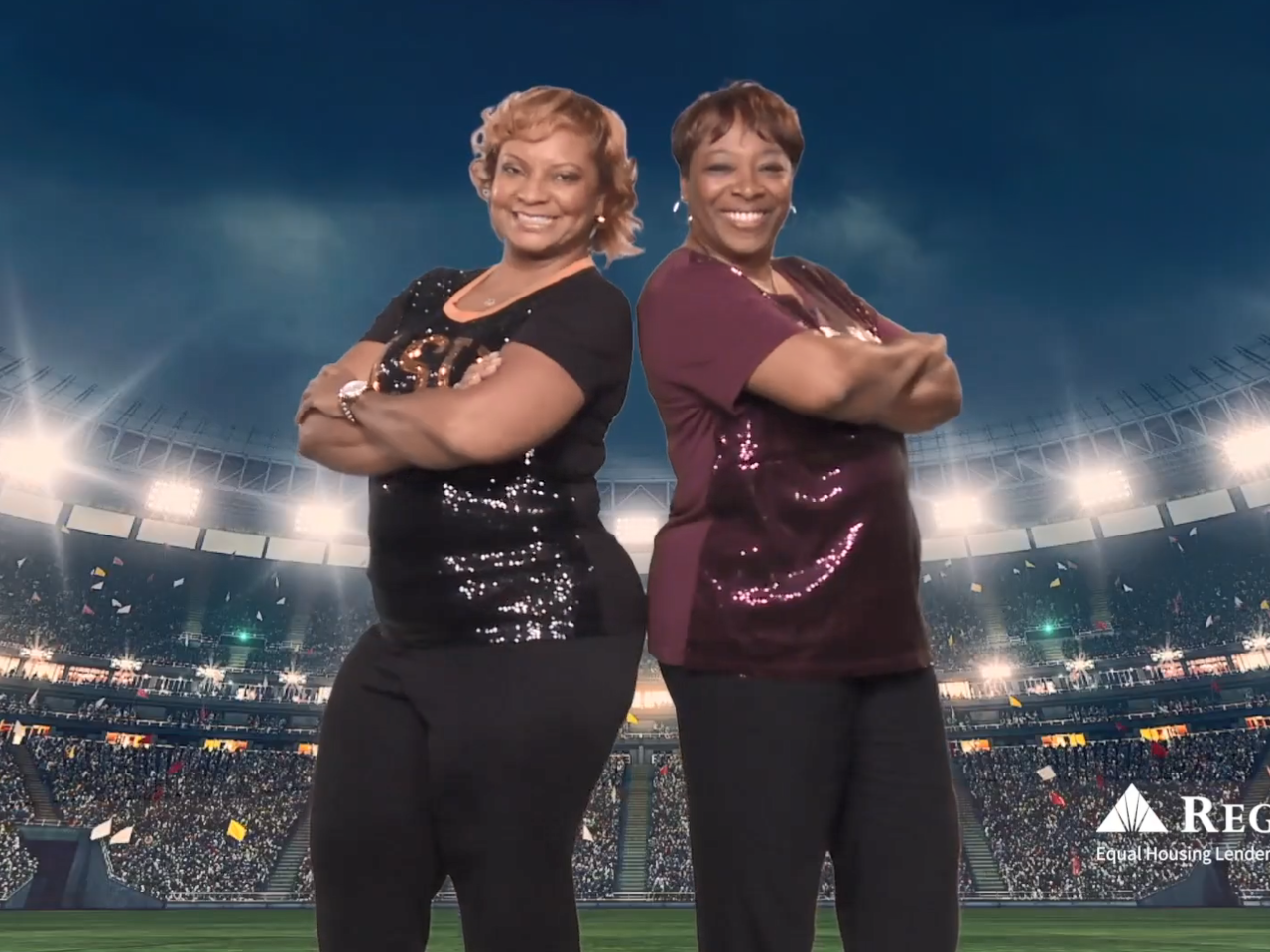 Two smiling people, leaning back to back with arms crossed. A stadium backdrop behind them.