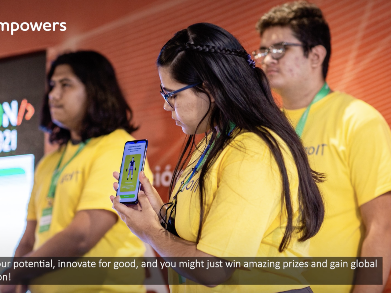 3 students showing off their app on stage