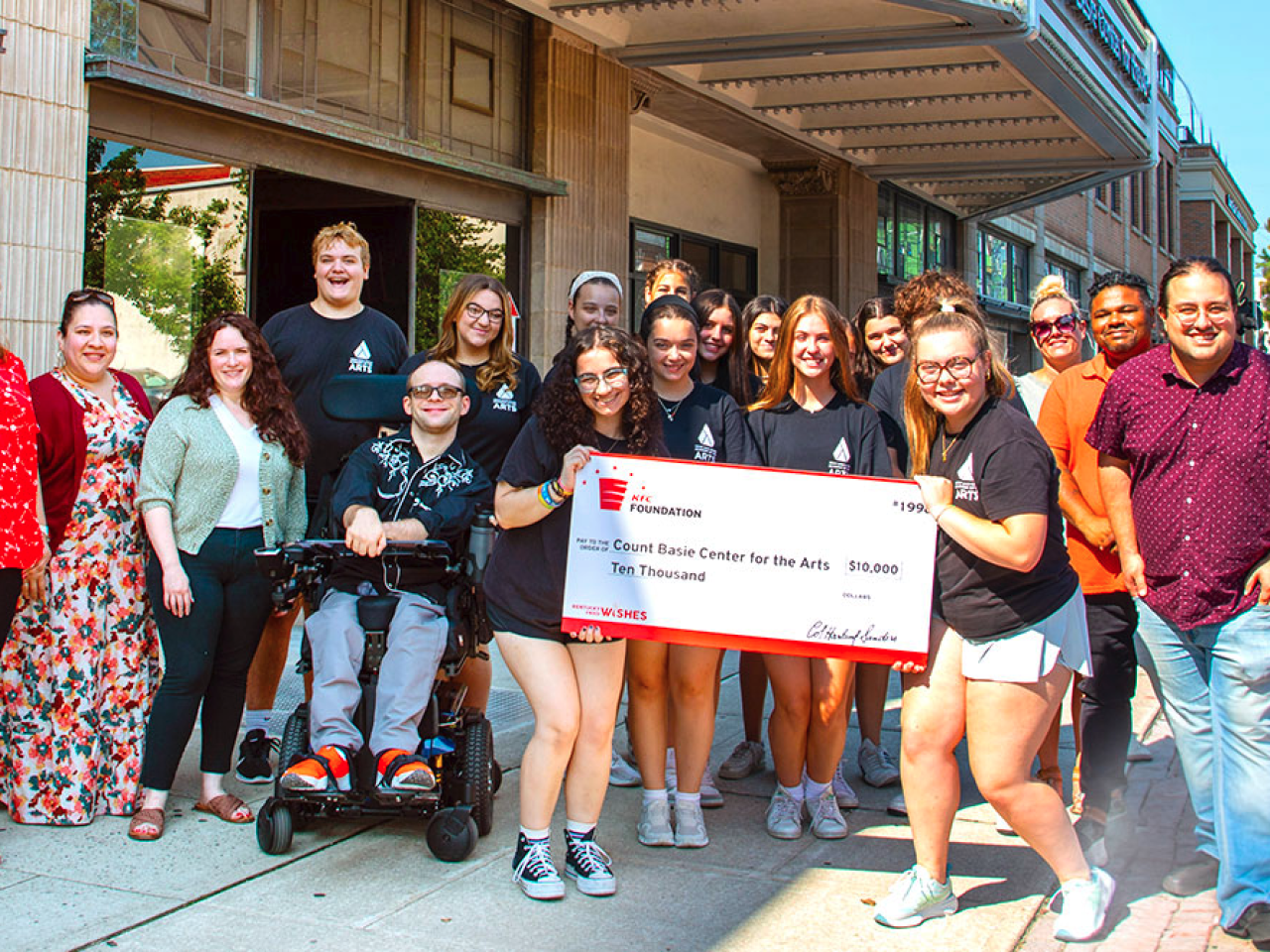 A group of people posing and smiling with an oversized check