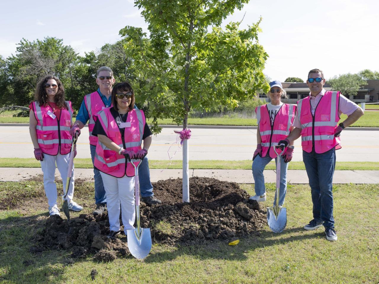 People in pink vests planting a tree