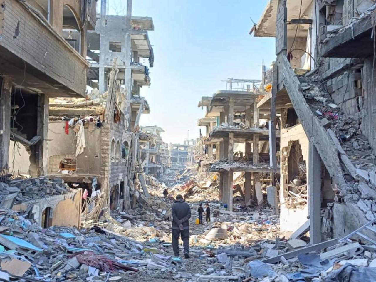 Man walks through street lined with destroyed buildings