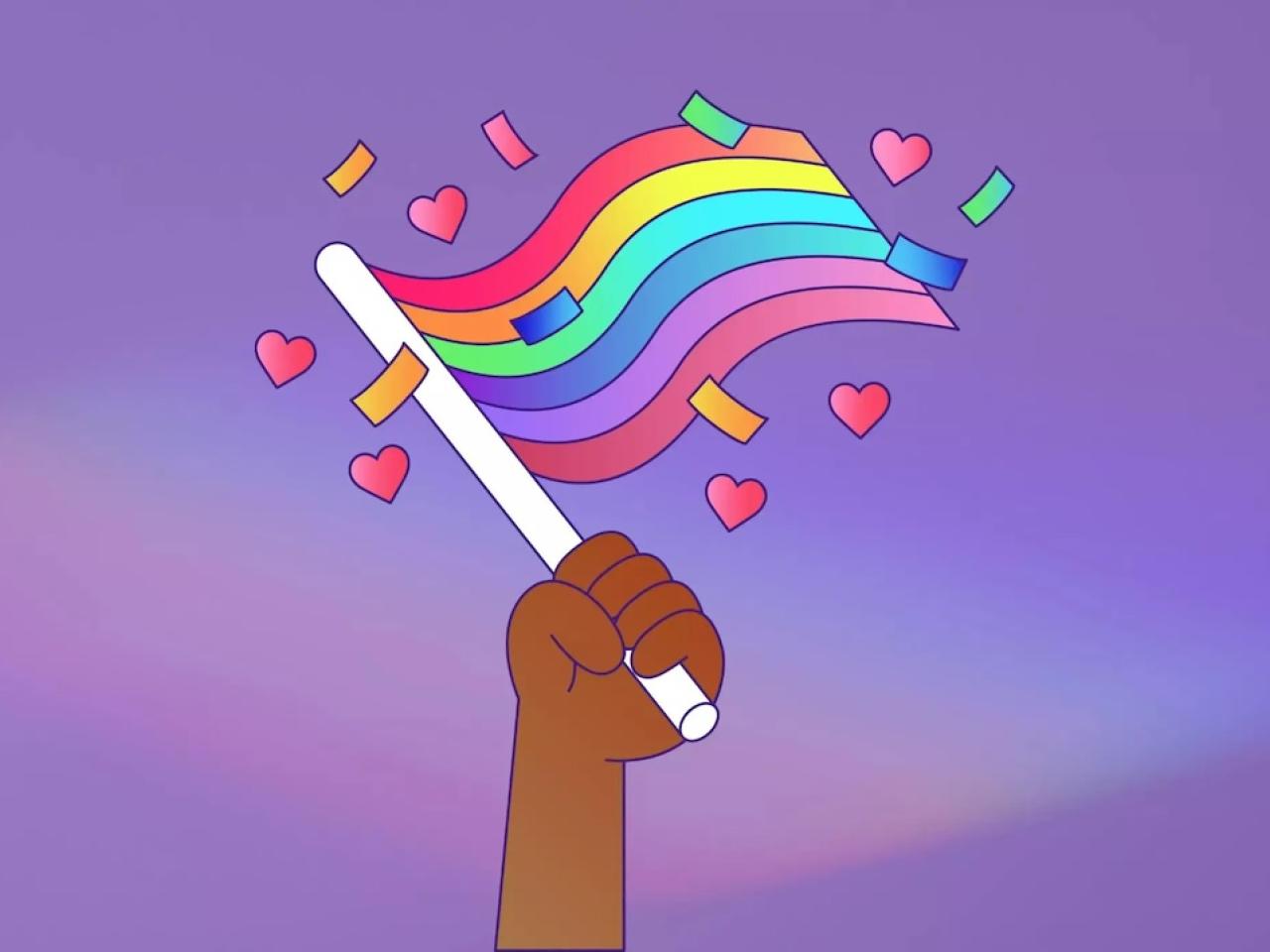All about Pride. A hand is shown holding a Pride rainbow flag.