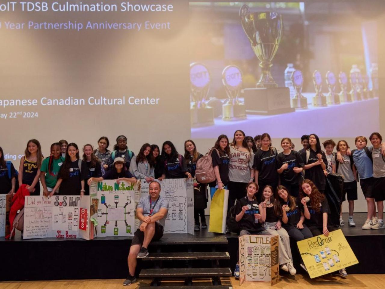 A group of students posed on a stage with project boards.