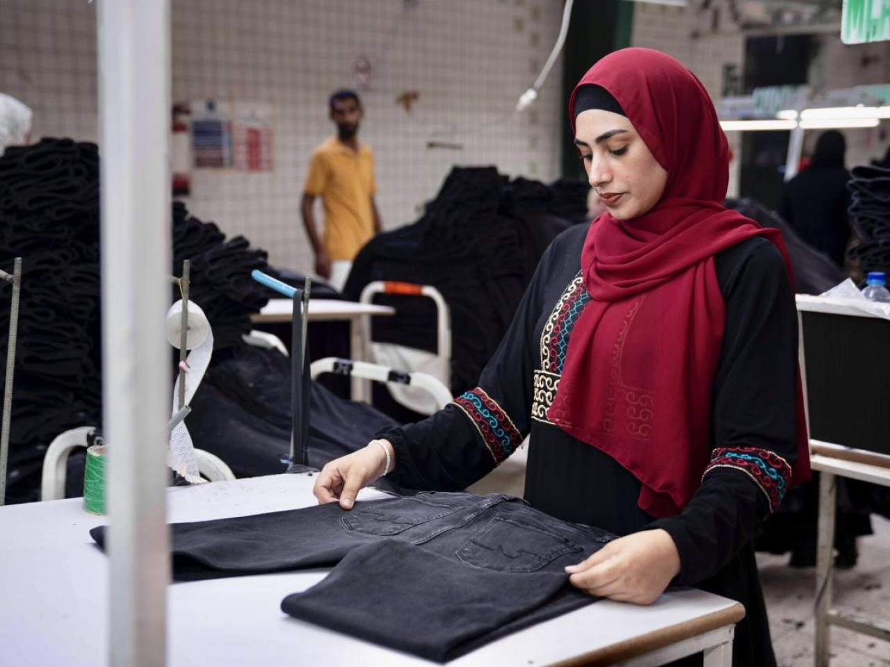 A garment worker folding a pair of jeans