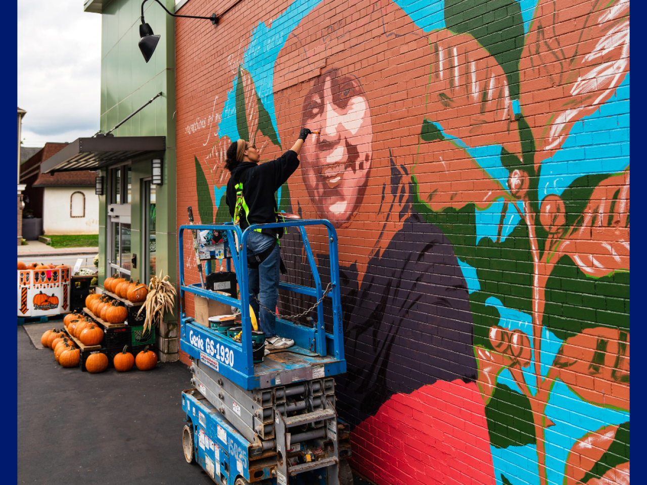 Artist Julia Bottoms paints a mural of Ibu Rahmah, a coffee farmer from Indonesia, outside Lexington Co-Op in Buffalo, NY.