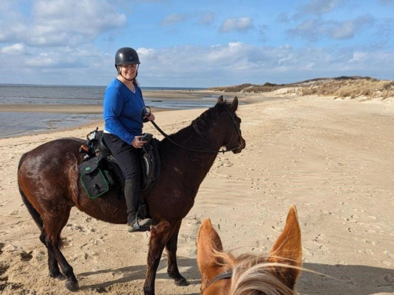 Julia Reilly riding a horse on a beach