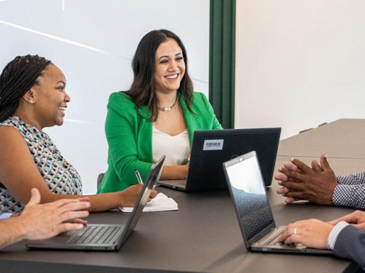 Lesly Luque and team at a conference table, some with open laptops.