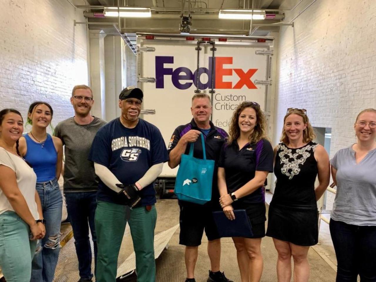 a group standing in front of a FedEx truck