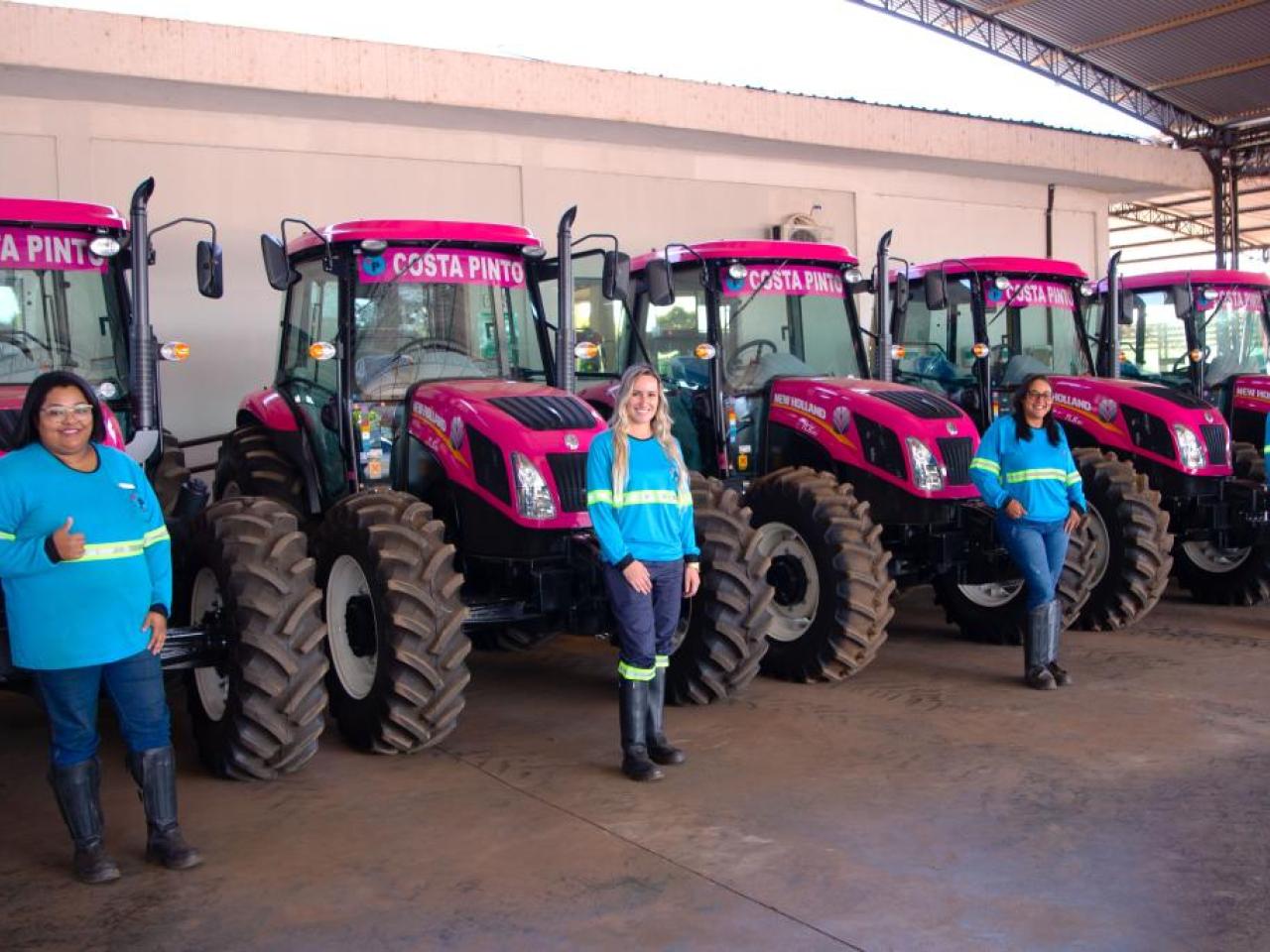 Women stood in a line in front of pink tractors 