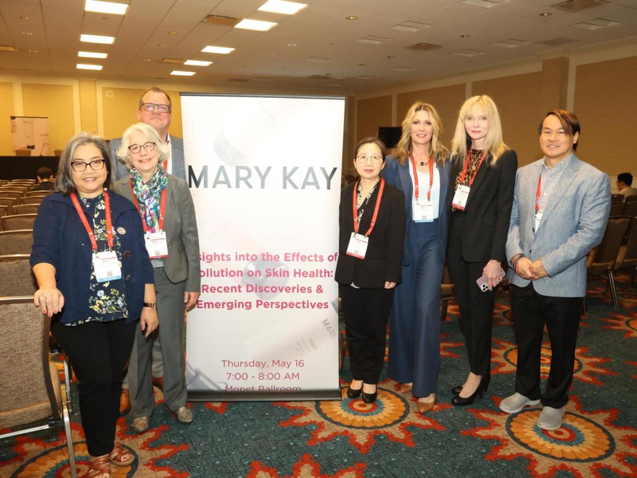 A group posed by a sign "Mary Kay" in a conference room.