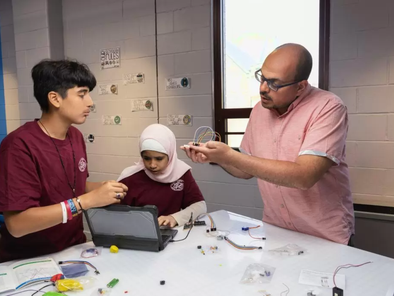 2 students and a teacher work on a project