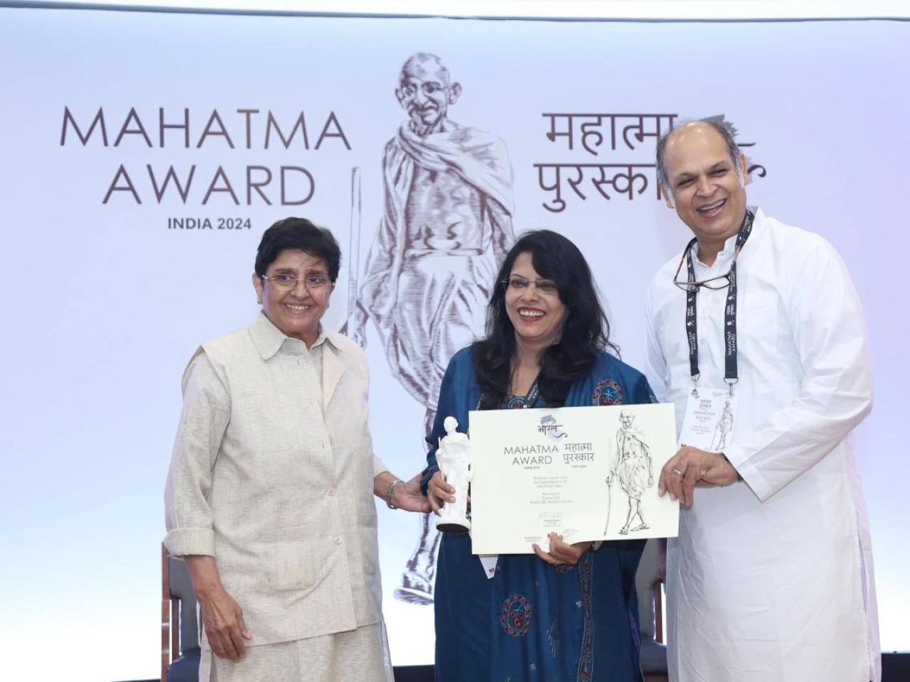 Kavita Sah and two others holding an award.