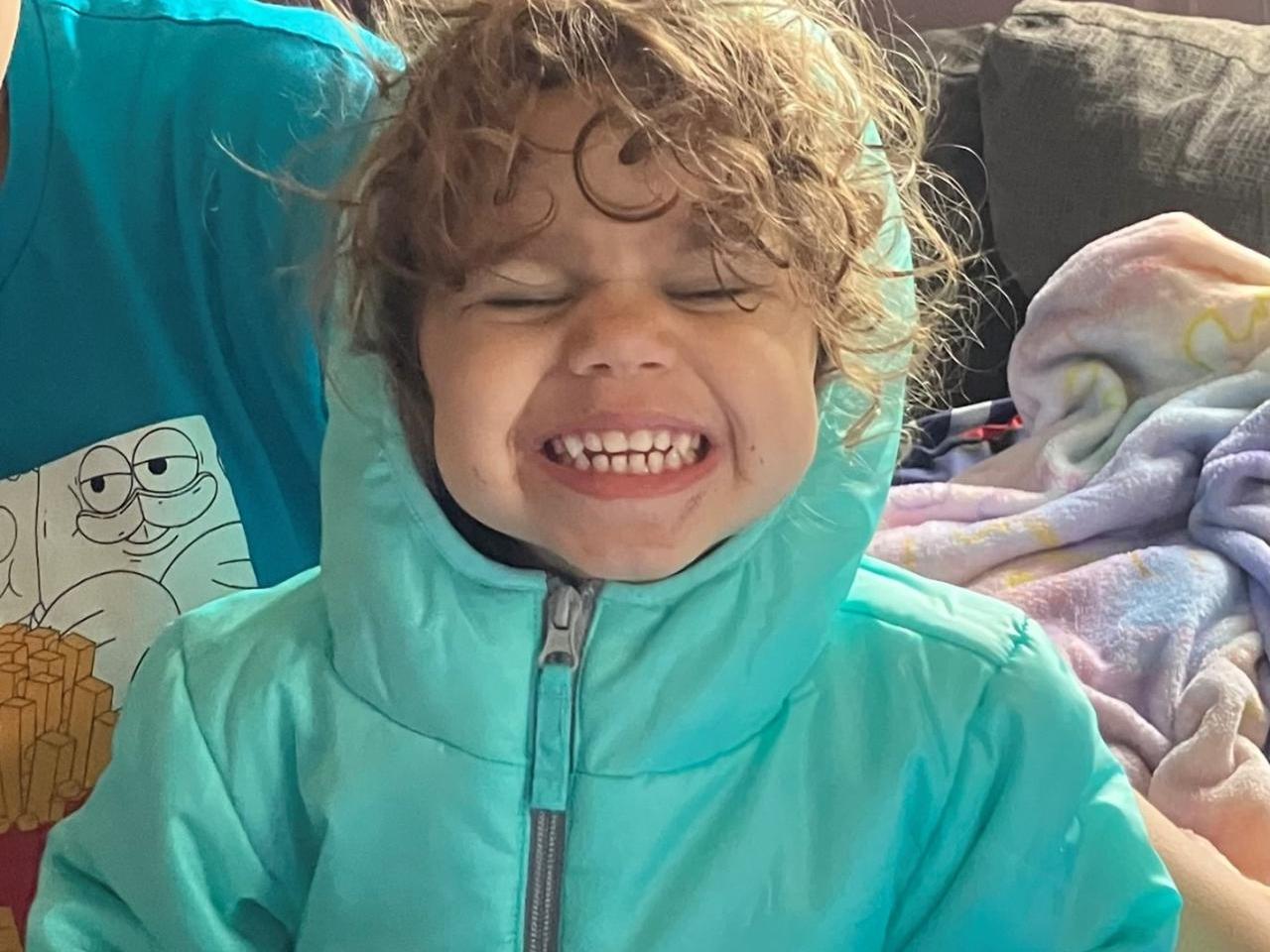 A smiling child in a teal coat