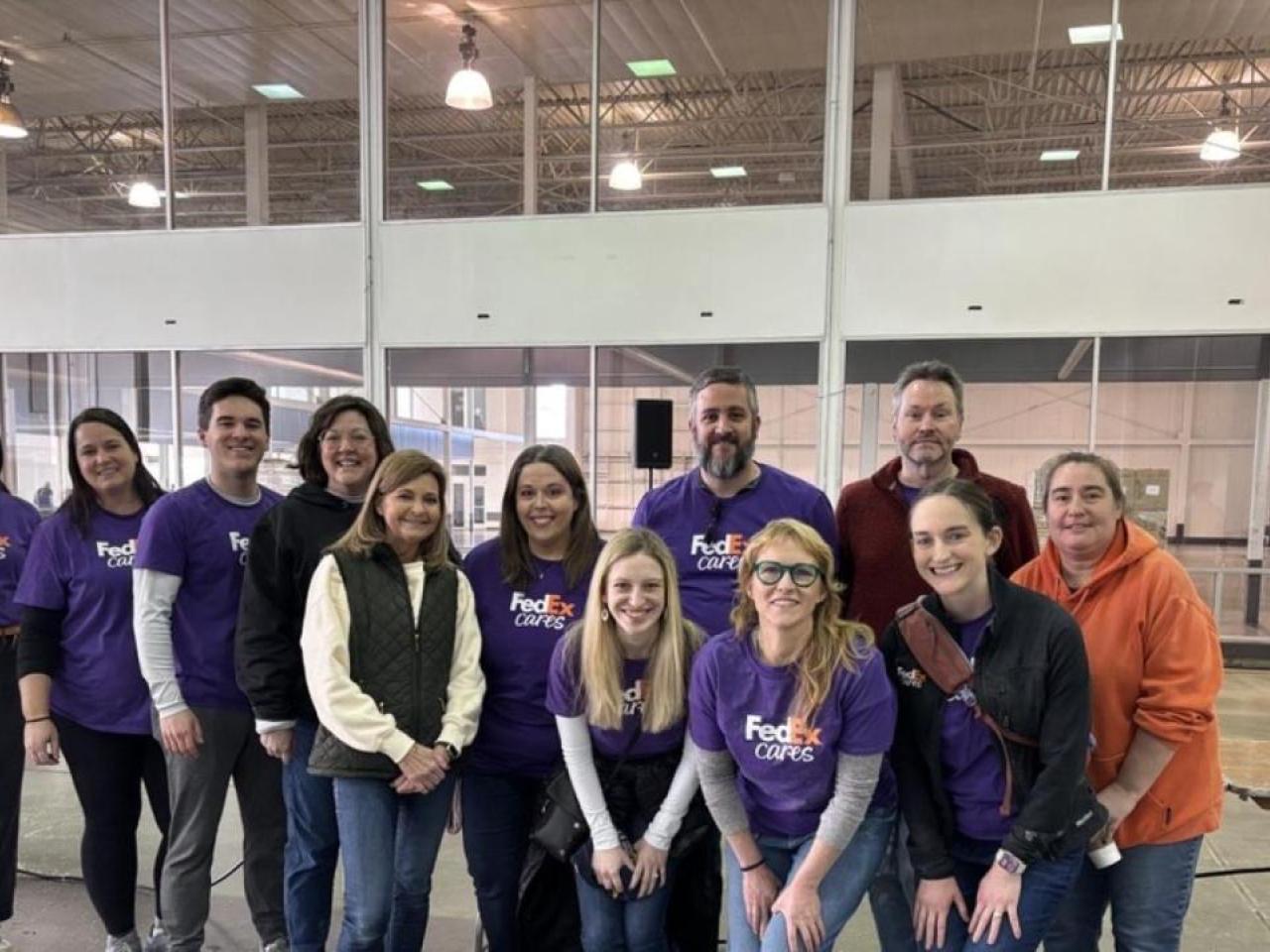 A group of people in FedEx Cares t-shirts posing inside a building