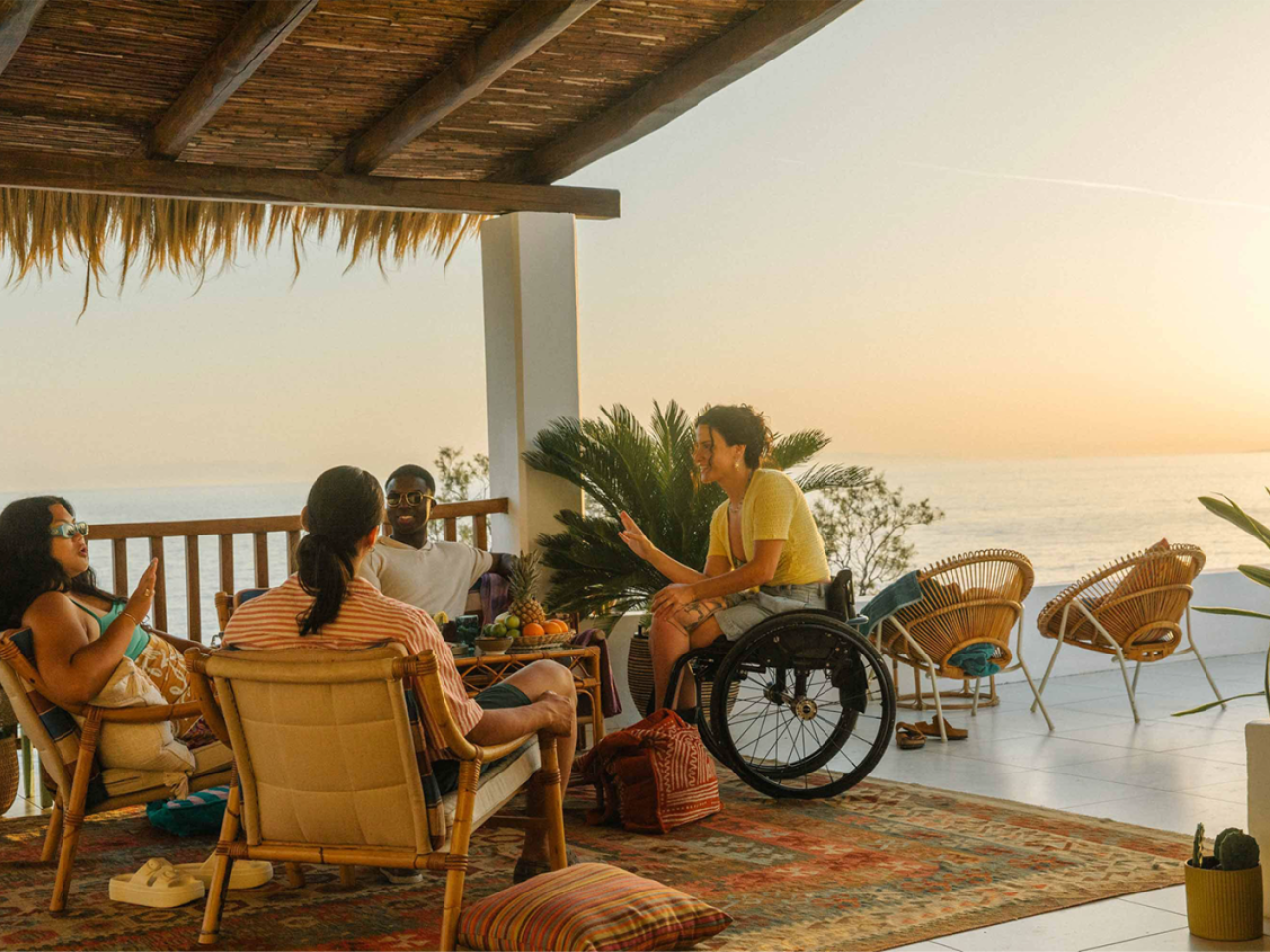 A group seated in a covered area overlooking an ocean expanse.