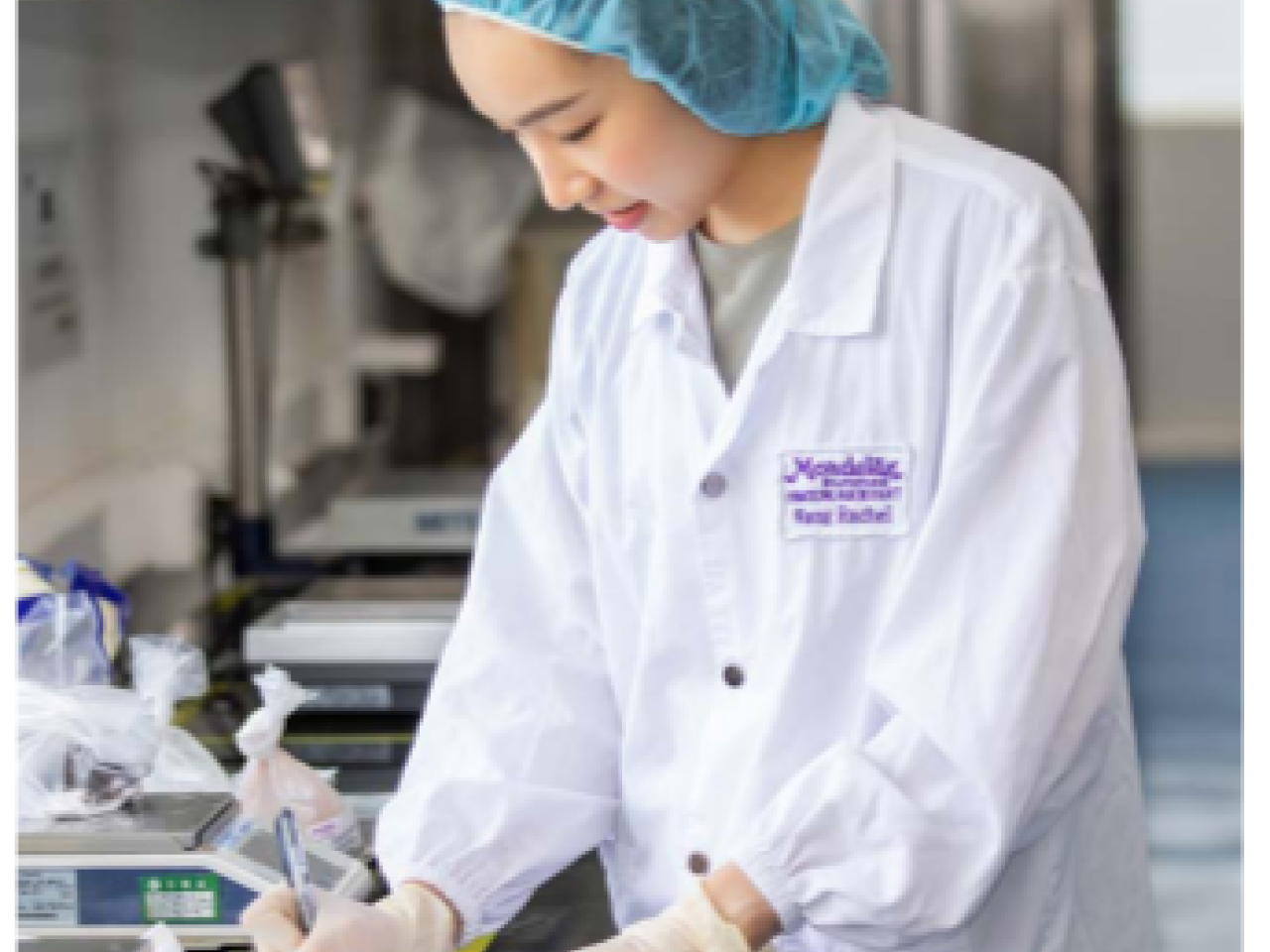 A person in protective lab gear making a note.