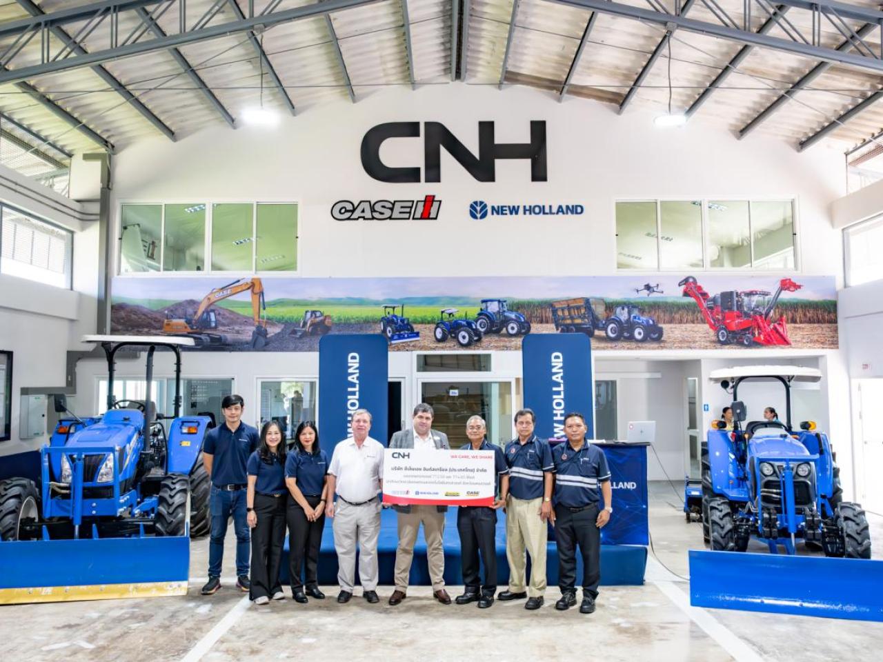 A group posed, some holding a large check, in a CNH showroom.