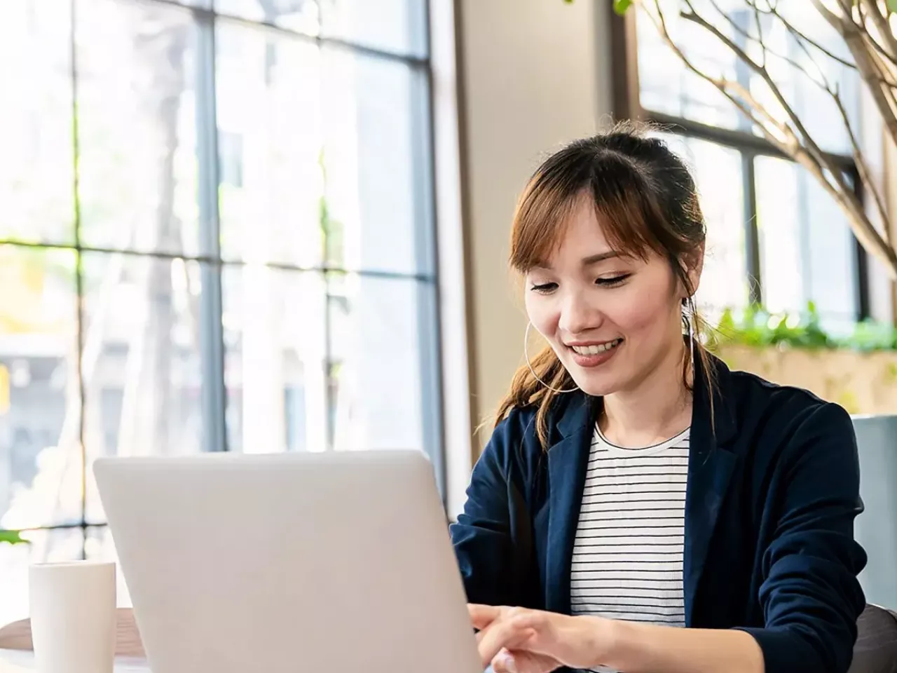 A person working on a laptop, next to a sunny window