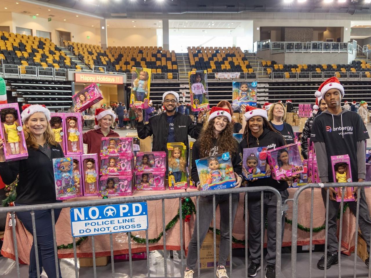 Volunteers holding up toys in a gymnasium.