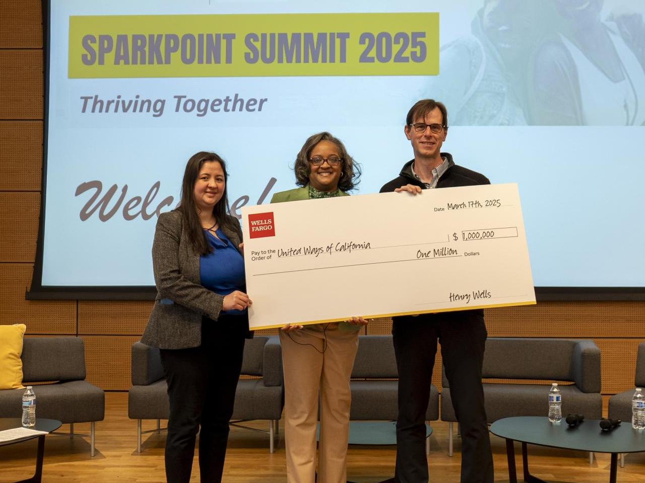 Three people, two women and one man, holding a big check