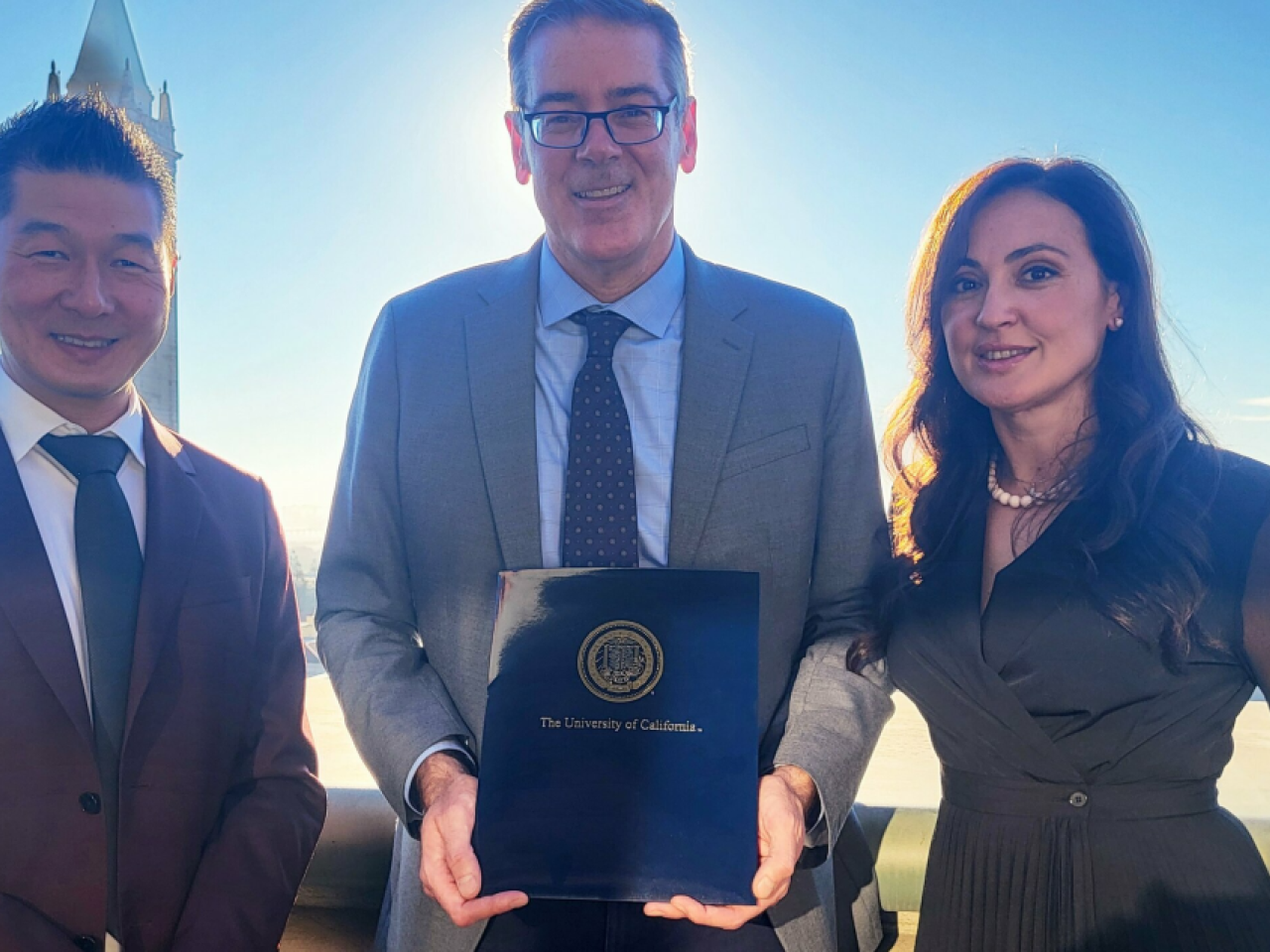 Three people standing together, holding a report