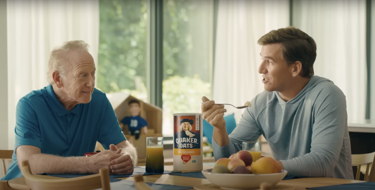 Two people sat at a dining table, one person eating a bowl of quaker oats