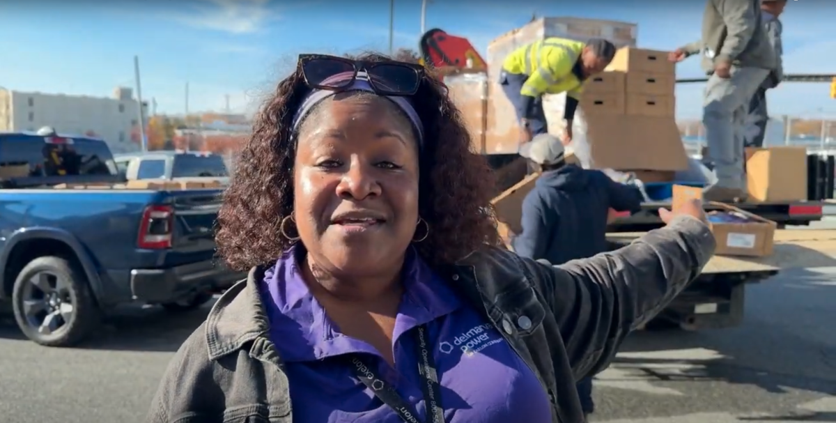 An employee speaks and gestures to people loading boxes on a truck