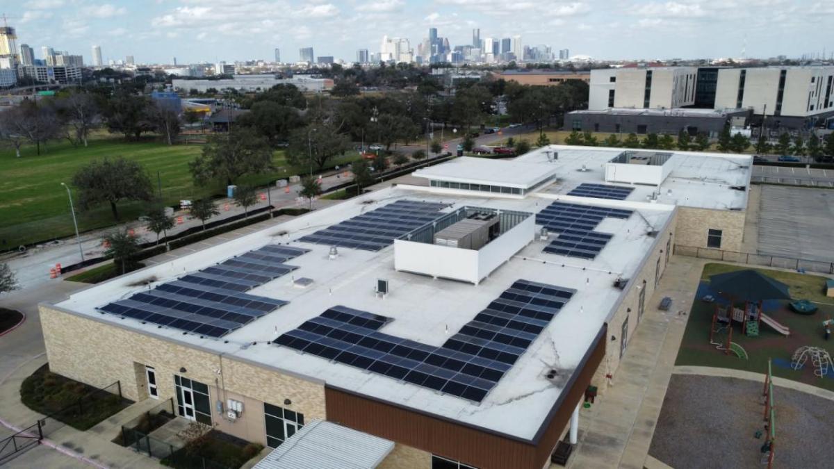 Solar panels on a roof with the Houston skyline in the background